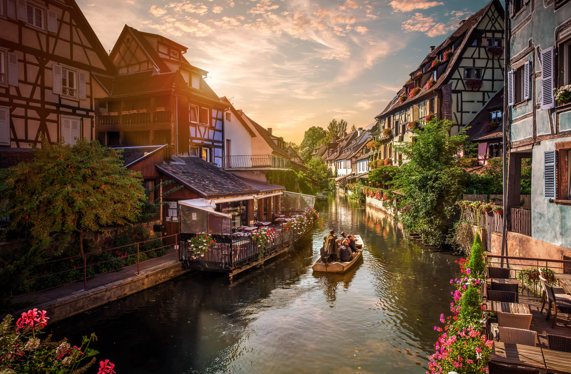 Kanal zwischen bunten Fachwerkhäusern mit Blumenkästen, ein Boot auf dem Wasser Kanal zwischen bunten Fachwerkhäusern mit Blumenkästen, ein Boot auf dem Wasser
